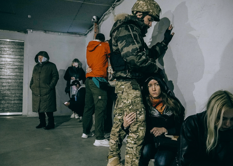 A soldier protects a woman in an underground parking lot near the drone strike in Kyiv on 17 October, 2022 © Julia Kochetova. A soldier protects a woman in an underground parking lot near the drone strike in Kyiv on 17 October, 2022 © Julia Kochetova.